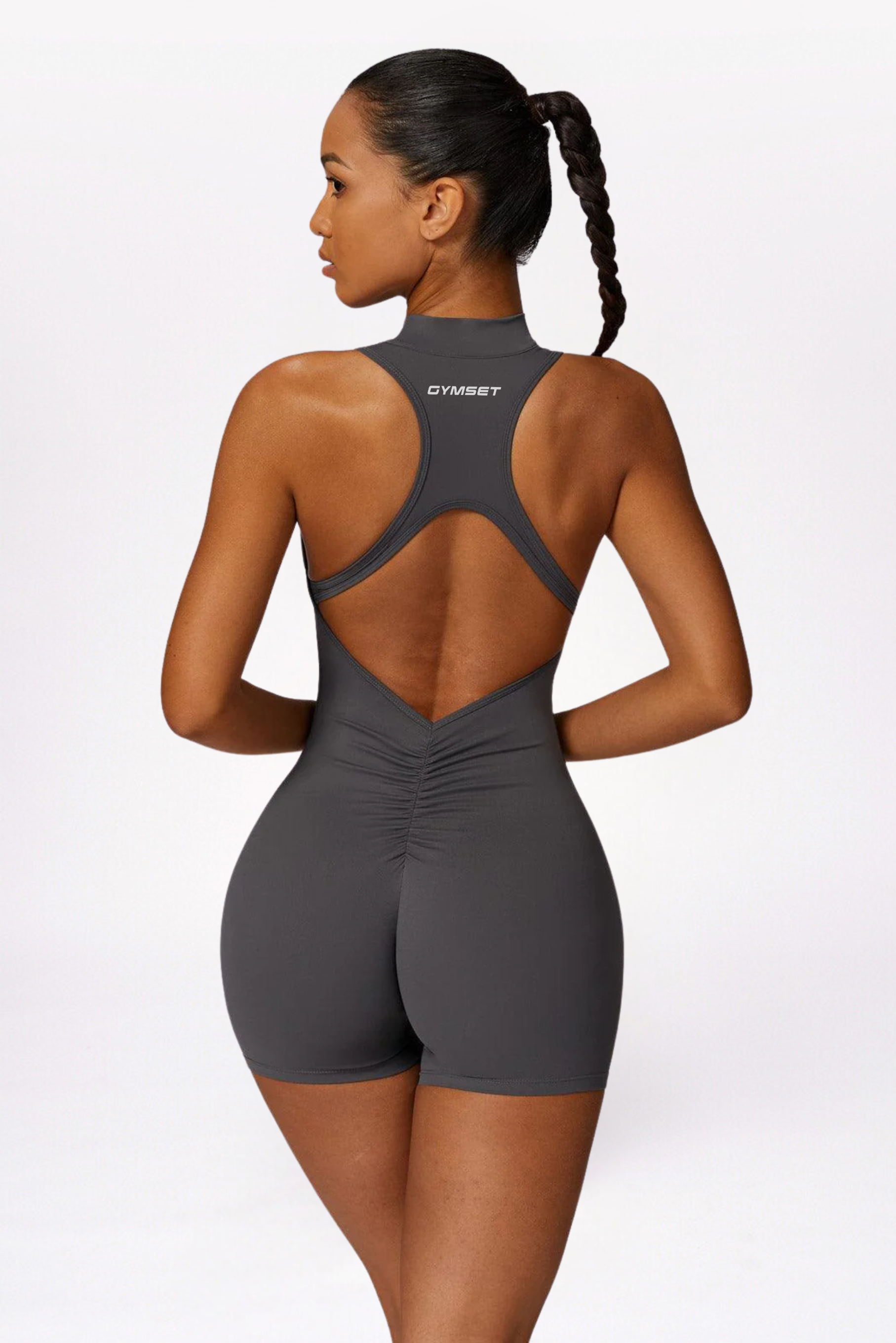 Woman wearing a gray open-back bodysuit on a white background brand Gymelle