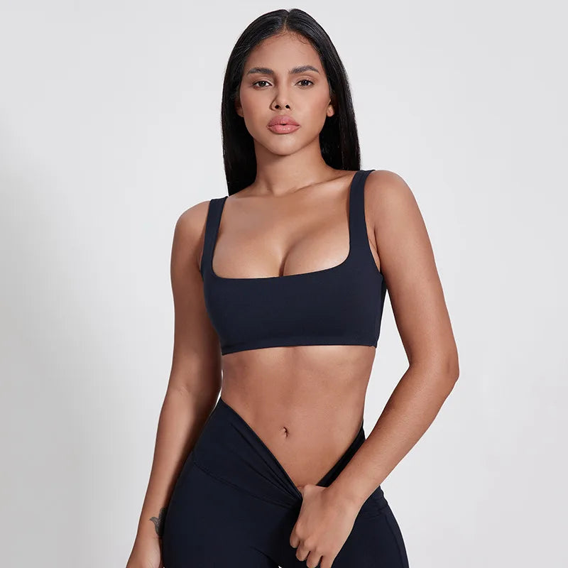 Woman wearing a black sports bra and leggings on a white background brand Gymelle