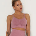 Woman wearing a pink sports bra and leggings against a white background