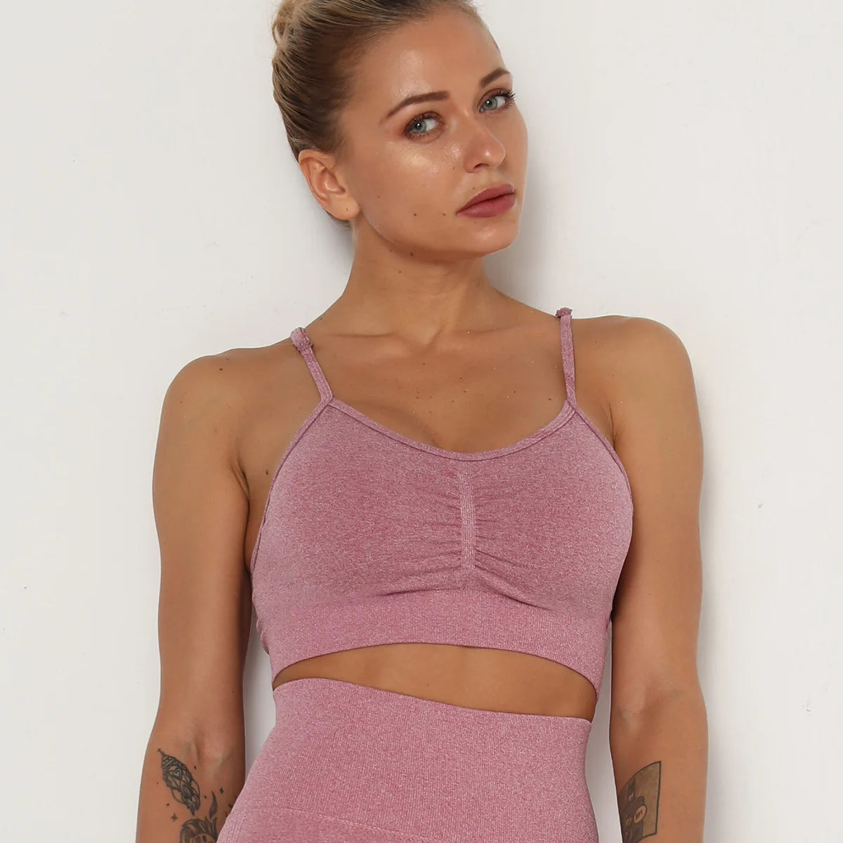 Woman wearing a pink sports bra and leggings against a white background