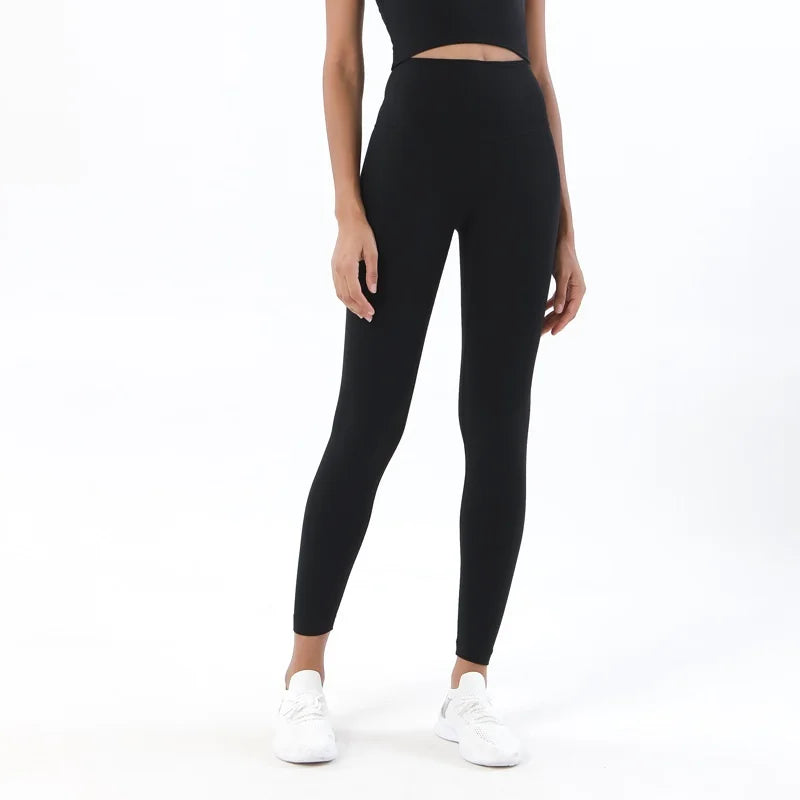 Person wearing black leggings and a black top on a white background